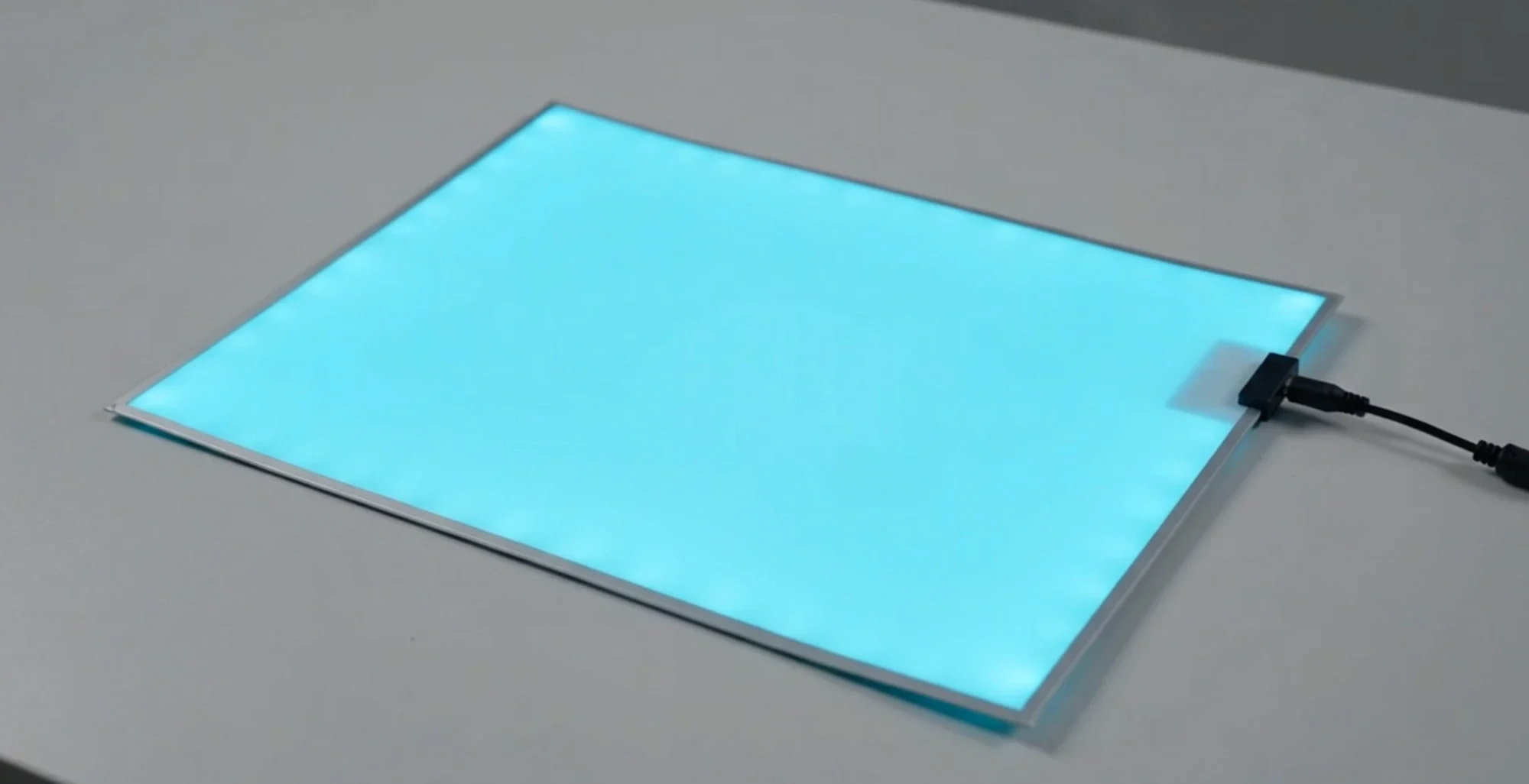 A complete STYELIGHTS™ EL panel glowing aqua on a table