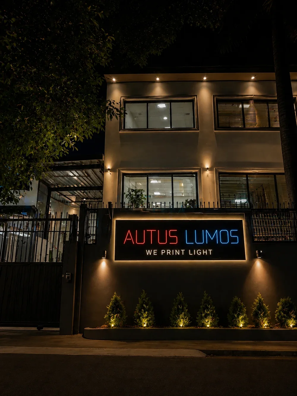 The Autus Lumos building at night, its “We Print Light” sign glowing red and blue